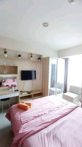 a bedroom with a large bed with a desk and a television at Transit 3jam Apartemen Grand Kamala lagoon bekasi in Pekayon Satu