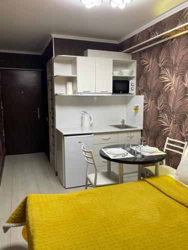 um quarto com uma cama, uma cozinha e uma mesa em Уютная комната-студия в центре Бишкека em Bishkek