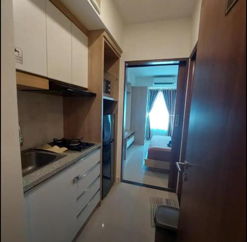 a kitchen with a sink and a room with a bed at Transit 3jam Apartemen Grand Kamala lagoon bekasi in Pekayon Satu