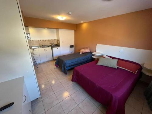 a room with a bed and a couch and a kitchen at complejo miligamapa con piscina climatizada in Villa Carlos Paz