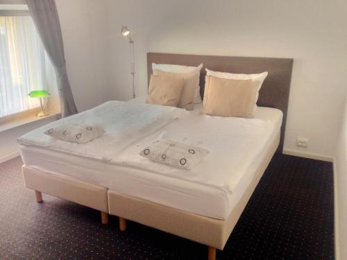 een groot bed met witte lakens en kussens erop bij Pension Flughafen Leipzig in Freiroda