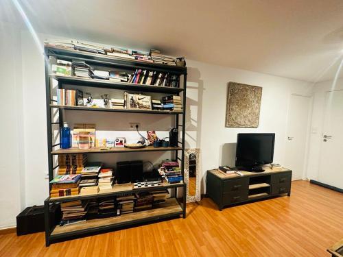 een kamer met een boekenplank met boeken en een televisie bij Apartamento 10 minutos de centro de Granada in Granada