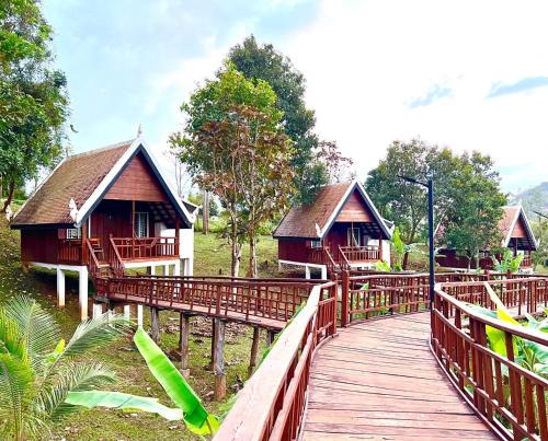 a wooden walkway leading to two cottages on a bridge at Greenhouse Retreat in Sen Monorom