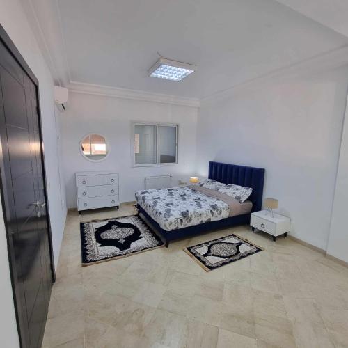 a bedroom with a bed and two rugs in it at Spacious Apartment Ennasr 2 in Ariana