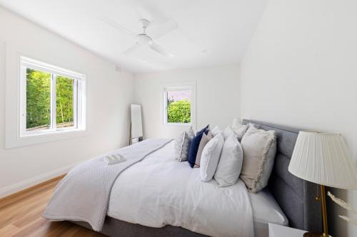 a white bedroom with a large bed with blue pillows at Little Manly 3 Bedroom Sanctuary in Sydney