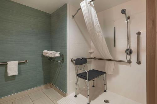 a bathroom with a shower and a chair in it at Best Western Plus New Englander in Woburn