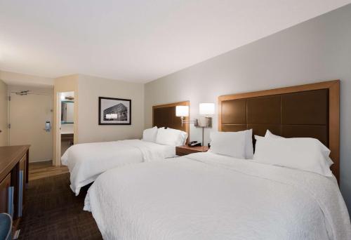 two beds in a hotel room with white sheets at Hampton Inn Columbia-I-26 Airport in Columbia