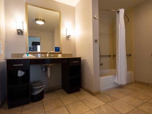 a bathroom with a sink and a mirror and a tub at Homewood Suites by Hilton Joplin in Joplin
