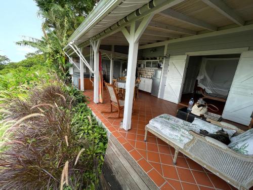 a porch of a house with couches and a kitchen at Beausejour Guest House in Pointe-Noire