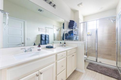 a white bathroom with two sinks and a shower at Cozy Condo in Round Rock in Round Rock