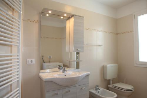 une salle de bain blanche avec un lavabo et des toilettes dans l'établissement Villa Bruna, à Lignano Sabbiadoro