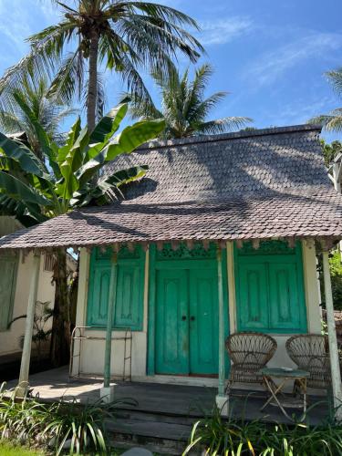 a house with a green door and two chairs at Captain Coconuts Gili Air in Gili Air