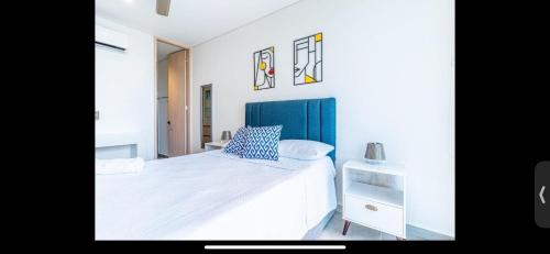a bedroom with a white bed with a blue headboard at Salguero suites resort in Gaira