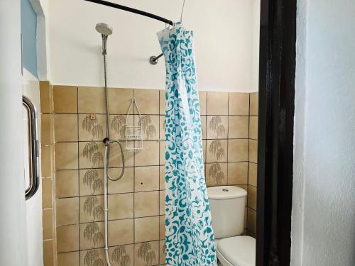 a bathroom with a shower curtain and a toilet at Carola's Garden in Willemstad