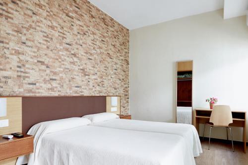 1 dormitorio con 2 camas y pared de ladrillo en Hostal Campo Nuevo, en Sanlúcar de Barrameda