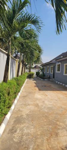 a driveway in front of a house with palm trees at THE PALMS VILLA GRA Sagamu in Sagamu