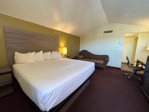 ChambersにあるSureStay by Best Western Chambers Petrified Forestの大きなベッドと椅子が備わるホテルルームです。