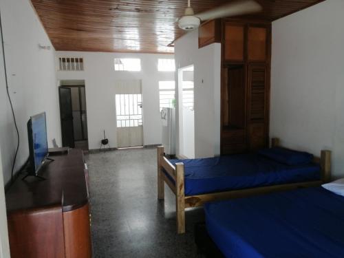 a room with two beds and a desk and a tv at Casa lowcost relajación in La Dorada