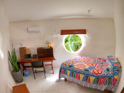 een slaapkamer met een bed, een bureau en een raam bij Casa ecológica surf e natureza in Camassari