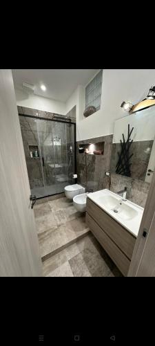 ein Badezimmer mit 2 Waschbecken, einer Dusche und 2 WCs in der Unterkunft Koman House in Savona