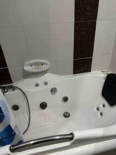 La salle de bains est pourvue d'une baignoire blanche et d'une douche. dans l'établissement Coin chaleureux coté plage, à Hammam Sousse