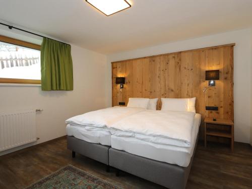 1 dormitorio con 1 cama grande y cabecero de madera en Apart Loisa en Pettneu am Arlberg