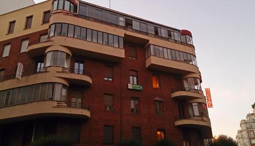a tall red brick building with balconies on it at Hostal Prada Borges in León