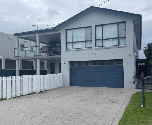 une grande maison blanche avec un garage bleu dans l'établissement Shellharbour Haven, à Shellharbour