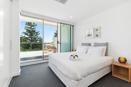 a bedroom with a large white bed and a large window at Belle Escapes - Sea the Views in Glenelg