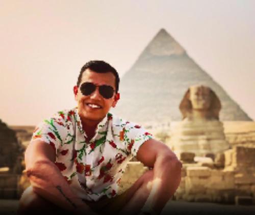 a man in sunglasses sitting in front of the pyramids at Sphinx view hotel in Ghaţāţī