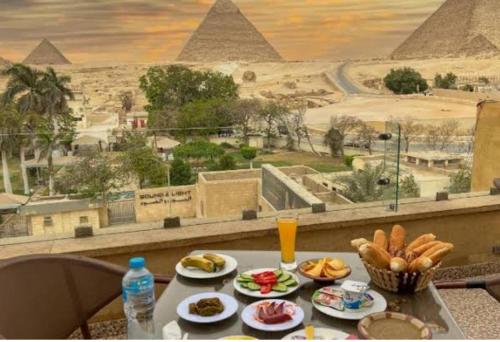 Sphinx view hotel في Ghaţāţī: طاولة صحون طعام وإطلالة على الاهرامات