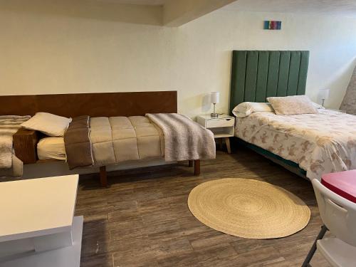 a hotel room with two beds and a rug at La casa del Petirrojo in Tequisquiapan