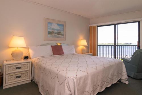 a bedroom with a bed and a balcony at Coquina Moorings 206 in Bradenton Beach