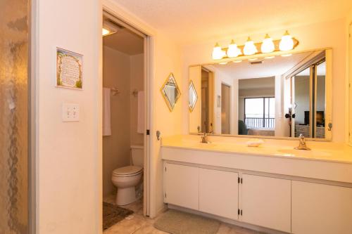 a bathroom with a sink and a toilet and a mirror at Coquina Moorings 206 in Bradenton Beach