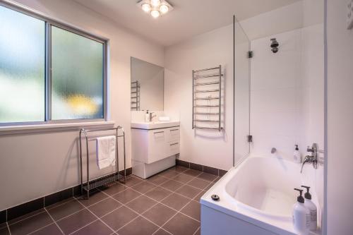 een witte badkamer met een bad en een wastafel bij Freycinet Haven in Coles Bay