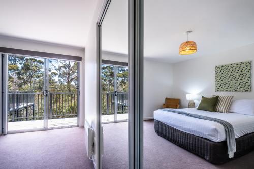 een slaapkamer met een bed en glazen schuifdeuren bij Freycinet Haven in Coles Bay