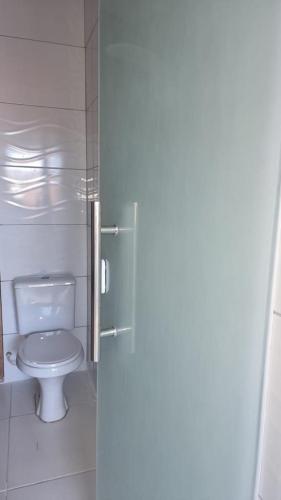 a bathroom with a toilet and a glass door at Apto em Itaparica condomínio in Itaparica Town