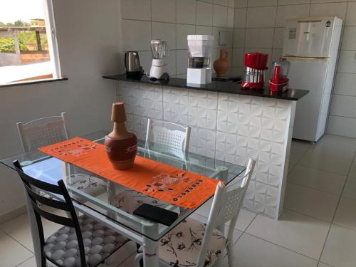 a kitchen with a glass table with chairs and a refrigerator at Apto em Itaparica condomínio in Itaparica Town