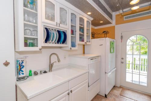 a kitchen with white cabinets and a white refrigerator at Sail Away Cottage in Bradenton Beach