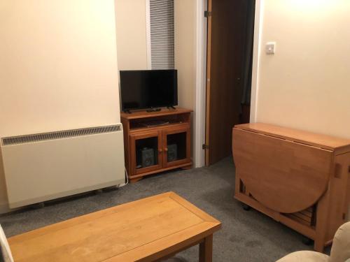 een woonkamer met een tv en een houten tafel bij Cosy flat, Scalloway in Scalloway