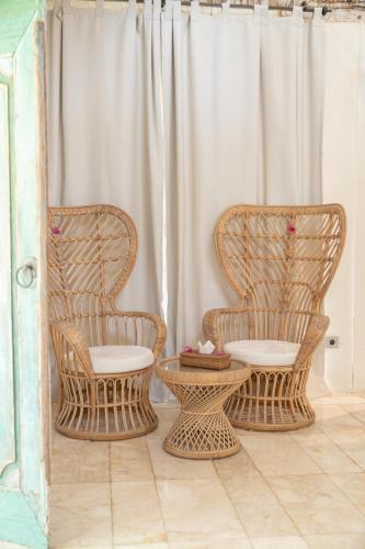 two wicker chairs and a table in front of a curtain at Captain Coconuts Gili Air in Gili Air