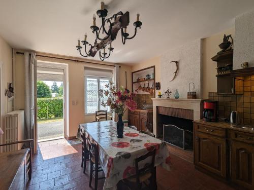 une cuisine avec une table avec un vase de fleurs dessus dans l'établissement Maison de Bourg avec Grand Jardin, Salle de Jeux et Confort Moderne – Près des Châteaux de la Loire - FR-1-591-161, à Préaux
