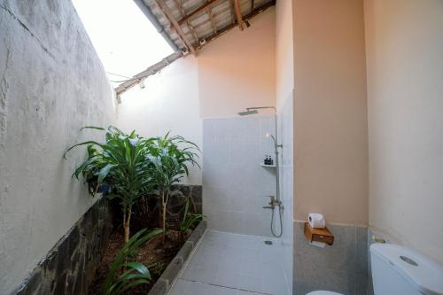 a bathroom with a shower and a plant at La Mer Resort, Phú Quốc in Phu Quoc