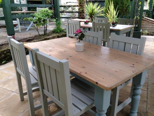 une table en bois avec des chaises blanches, une table, une table et des chaises dans l'établissement The Waterman's Arms, à Totnes