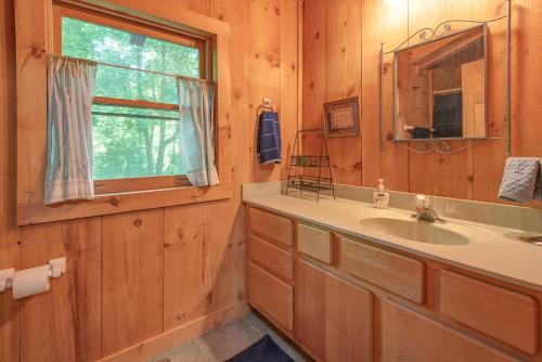 baño con lavabo, espejo y ventana en River Retreat Cabin en Arden