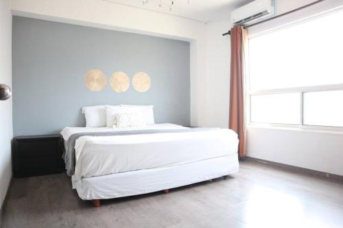 um quarto com uma cama com lençóis brancos e uma janela em Amplio depa 10 min Parque Fundidora, Estadio BBVA - LV5 - em Monterrey