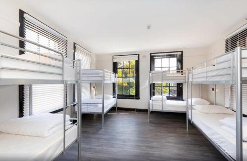 a room with four bunk beds and two windows at The Lansdowne Hotel in Sydney