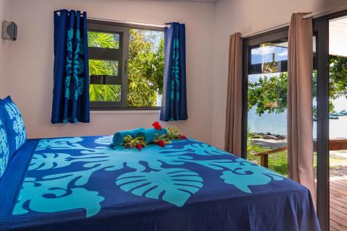 a bedroom with a blue bed with flowers on it at Matira Beach Raitea 1 in Bora Bora