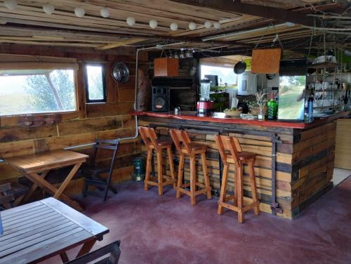 a bar in a restaurant with wooden stools at Las Chuñas in Villa Yacanto