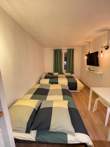 two beds in a small room with green curtains at T2D Apartment - Suite TVR proche Disneyland Paris in Bussy-Saint-Georges